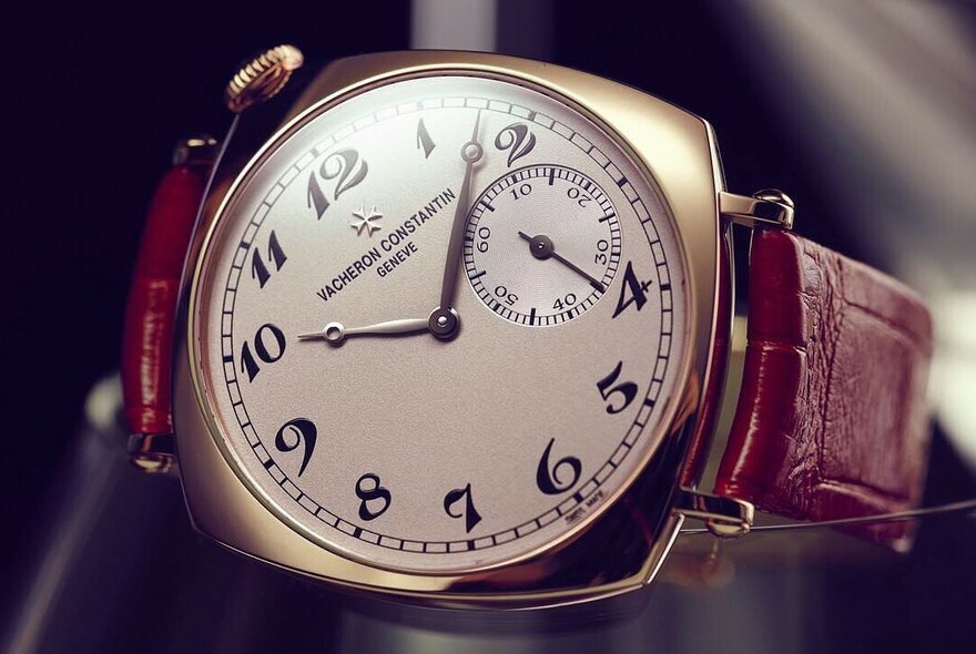 Vintage-style watch with numerals and inset seconds timer on leather strap.