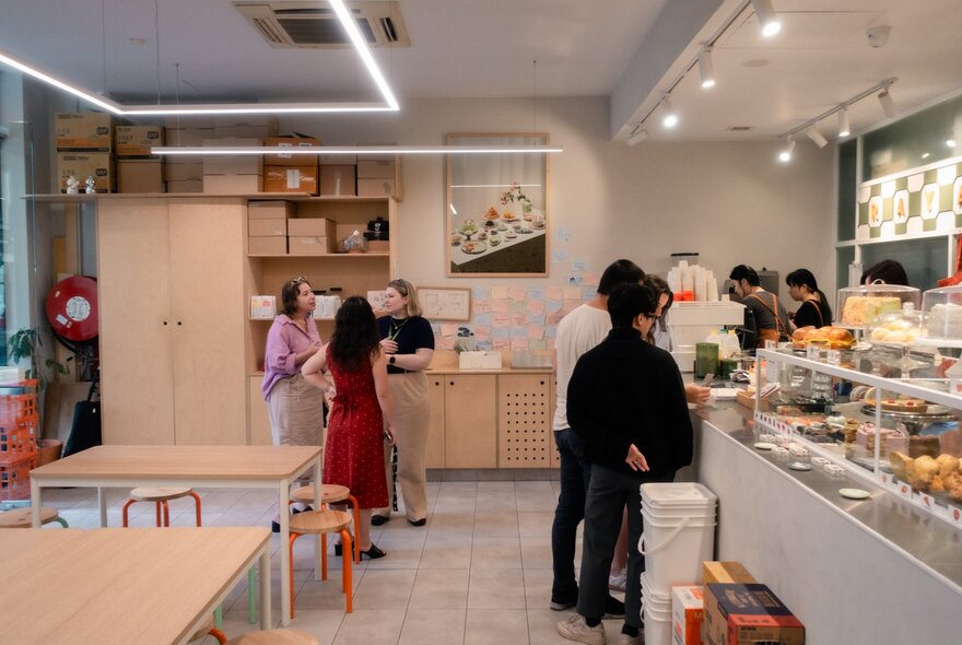 Bright, clean cafe with people being served and wooden counters.