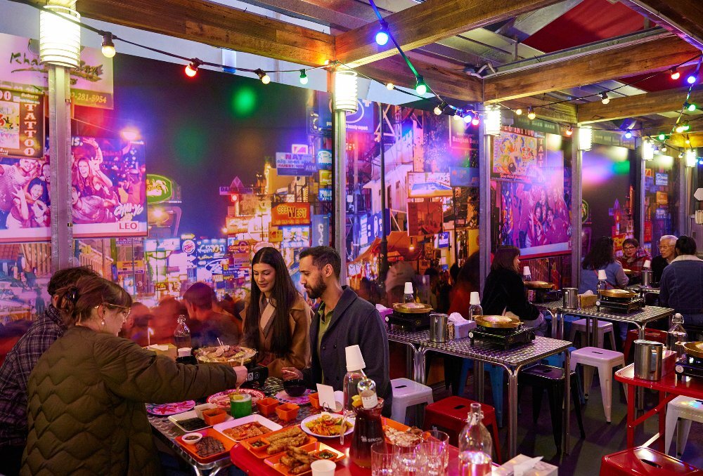 A group of friends are in a laneway Thai restaurant eating 