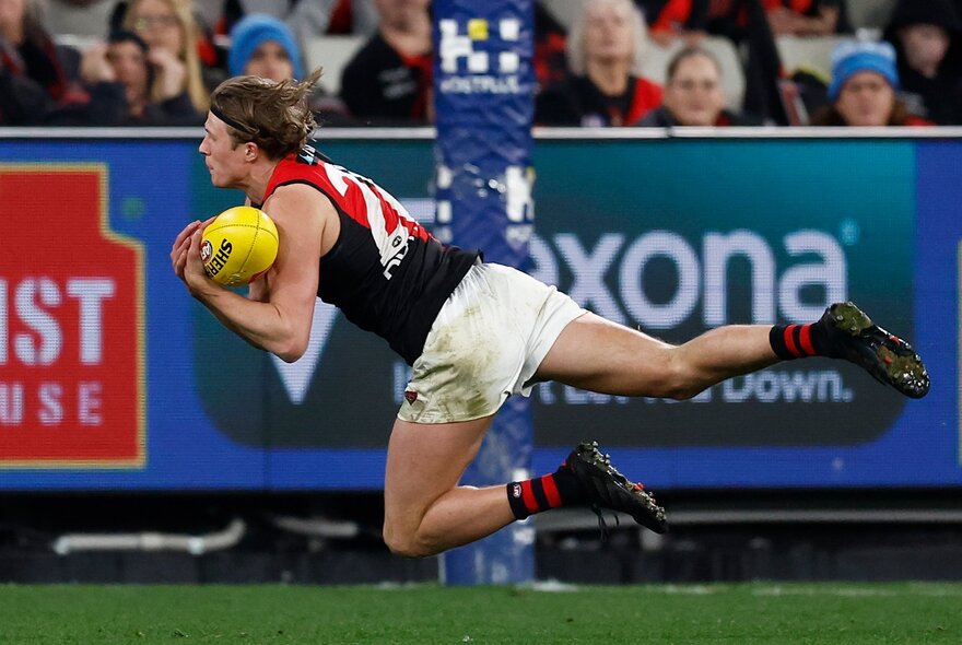 Essendon AFL football player flying to catch the ball during a match.