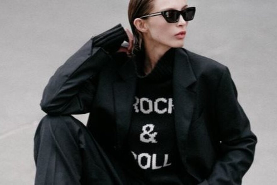 Model wearing a branded sweatshirt, jacket and sunglasses.
