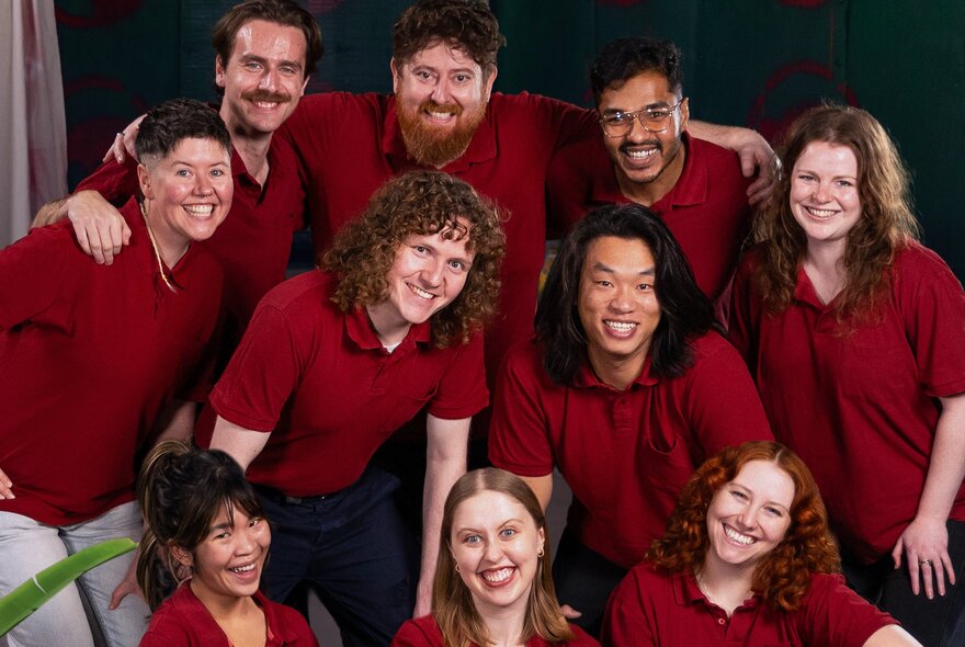 A troop of performers in red polos smiling for a group photo. 