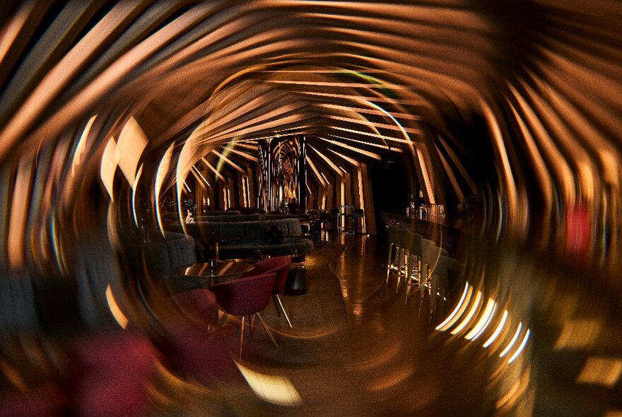 The cocoon-like interior space of Curious bar, with textured wall, and small groupings of round tables and club chairs.