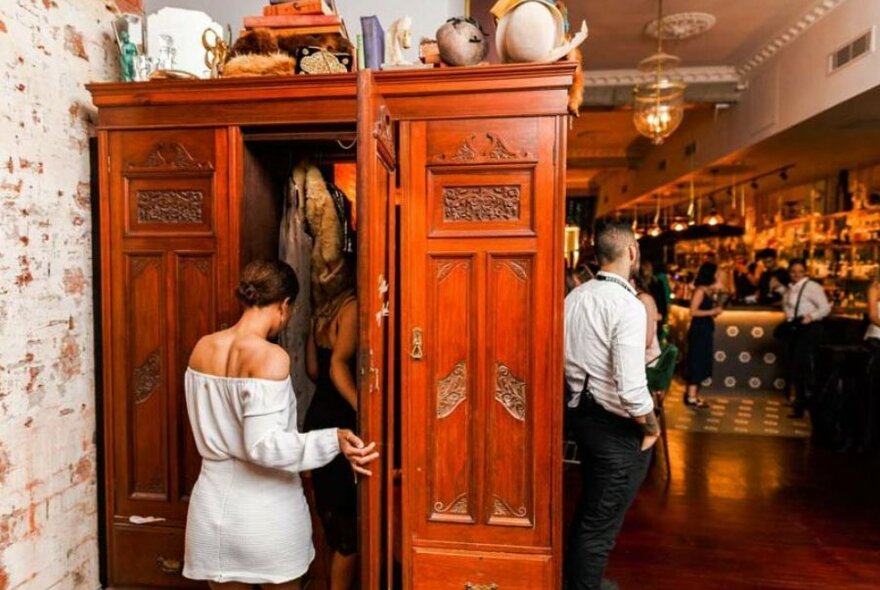 A woman entering a secret wardrobe at Trinket bar. 