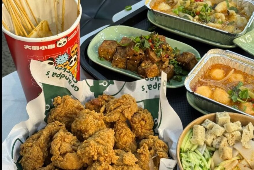 Selection of Chinese food on plates including fried chicken, soup and stir fries.