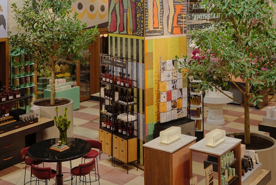 A beauty store with trees and products displayed around a colourful mosaic tiled pillar.