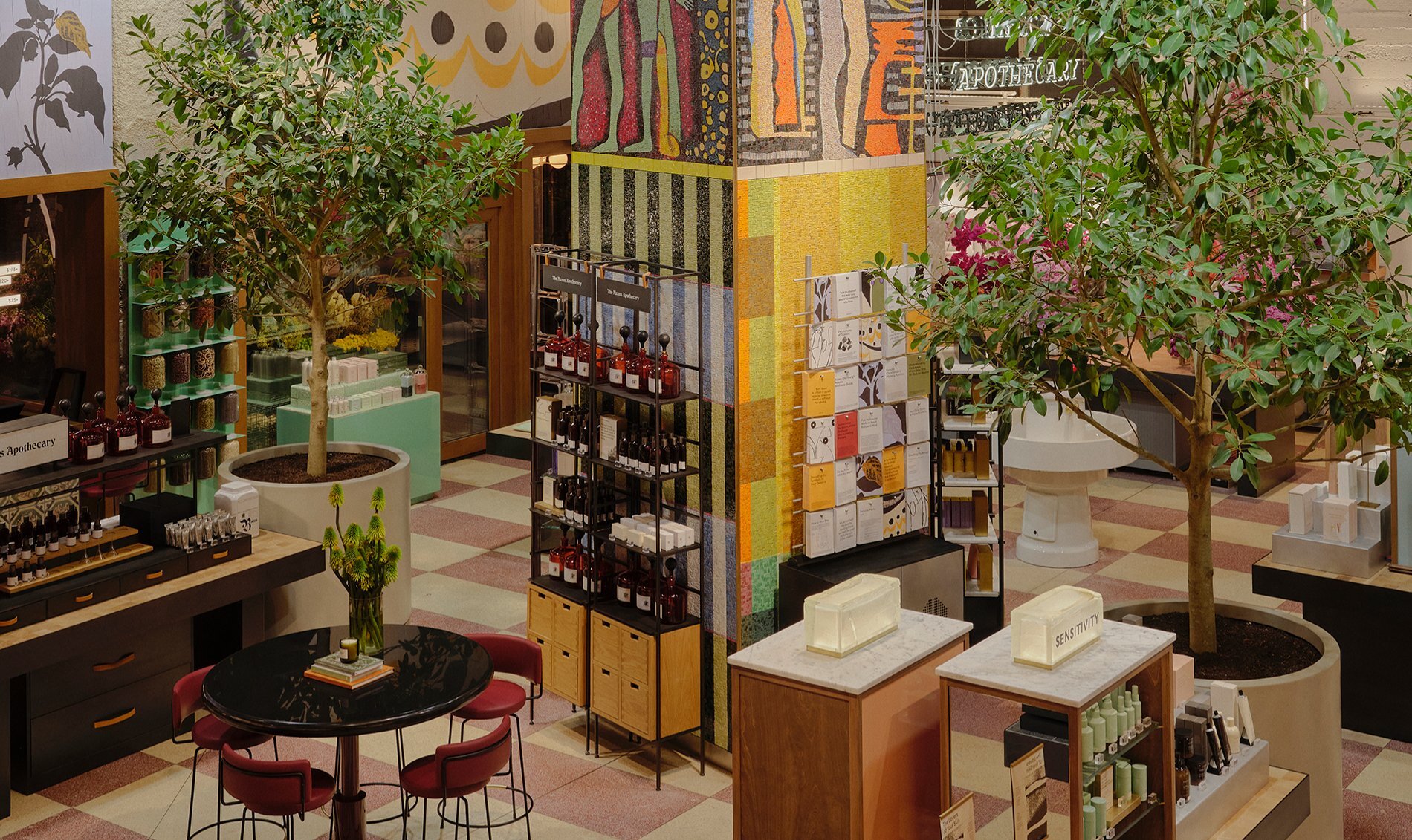 A beauty store with trees and products displayed around a colourful mosaic tiled pillar.