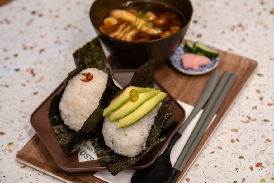 Two onigiri on a wooden tray with a small soup.