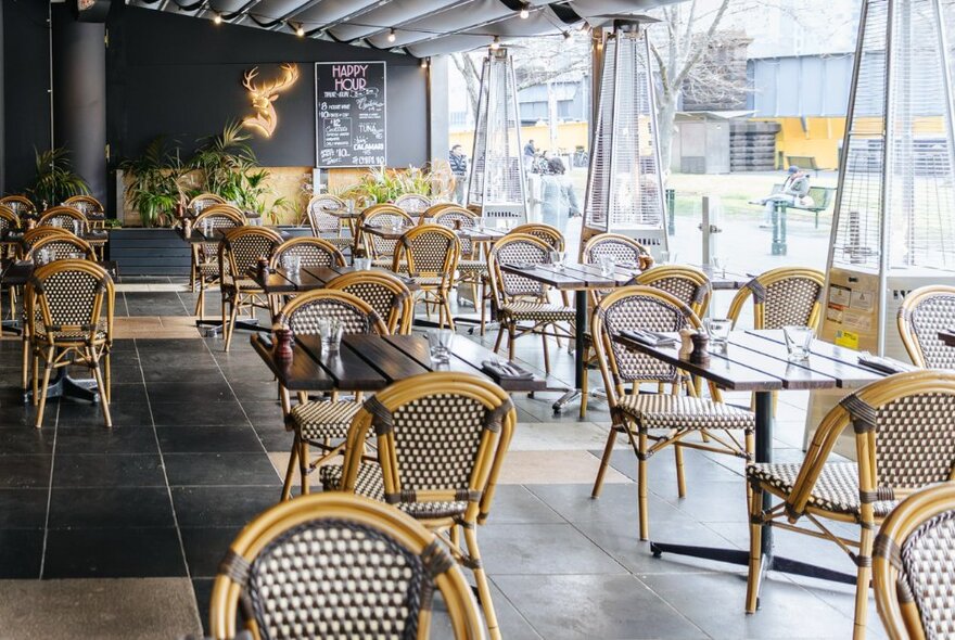 Interior of a restaurant with a tiled floor, dining tables and rattan dining chairs.