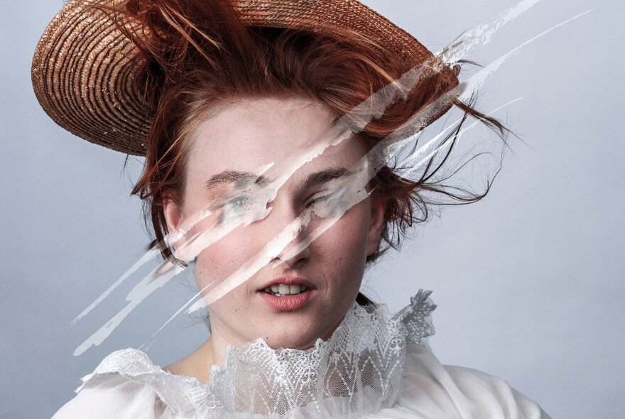 Image of a woman wearing vintage dress and hat, her face scratched with white.