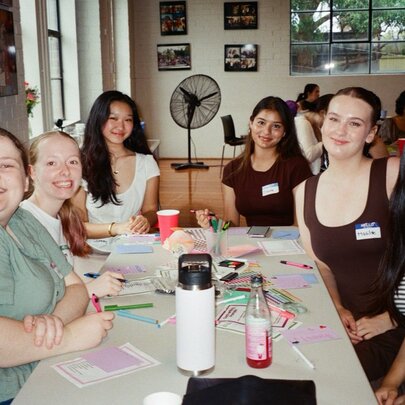 A group of people seated around a table at a crafting event, indoors.