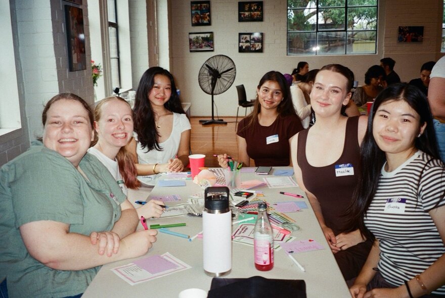 A group of people seated around a table at a crafting event, indoors.