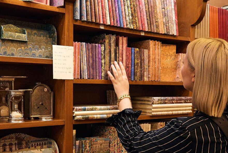 A woman looking at marbled notebooks in a stationary store.