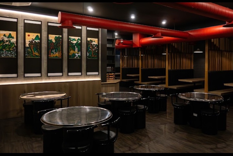 The interior of a restaurant with round tables and chairs arranged in the space. 