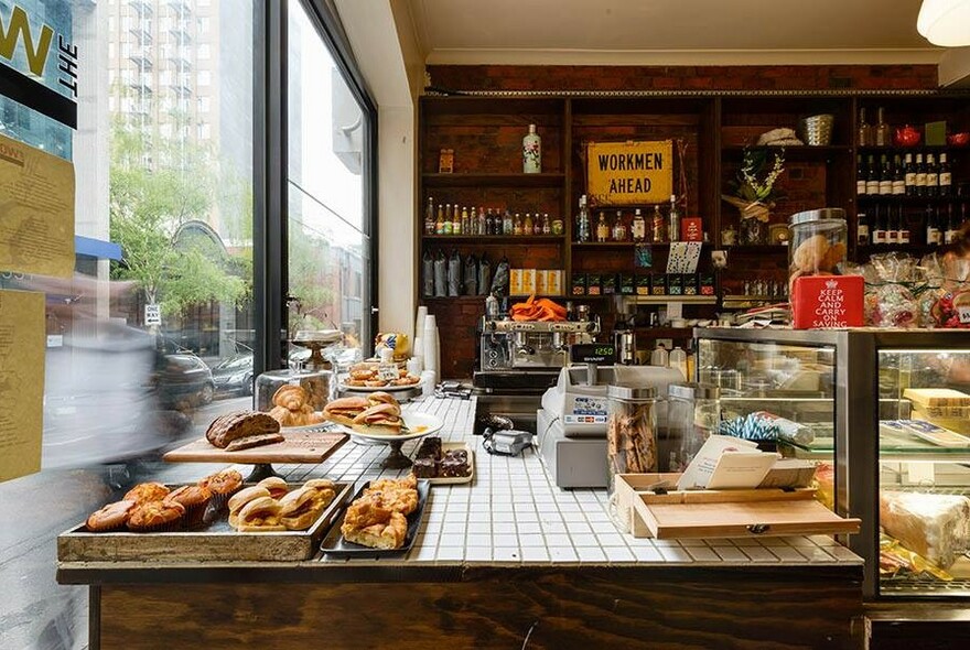 Interior of the a cafe showing front counter filled with food.