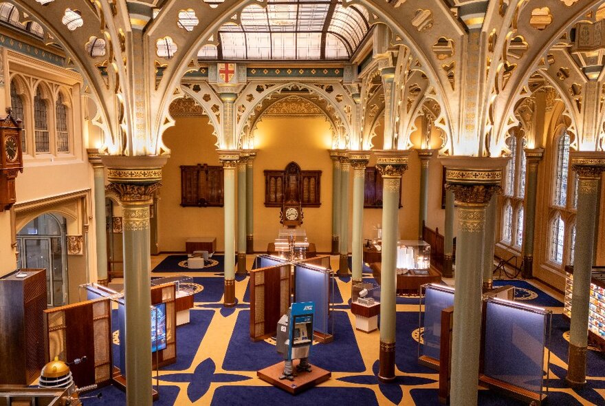 Bird's eye view of the ornate  interior of the Gothic Bank foyer, showing display stands, columns, and royal blue and gold carpet on the floors. 