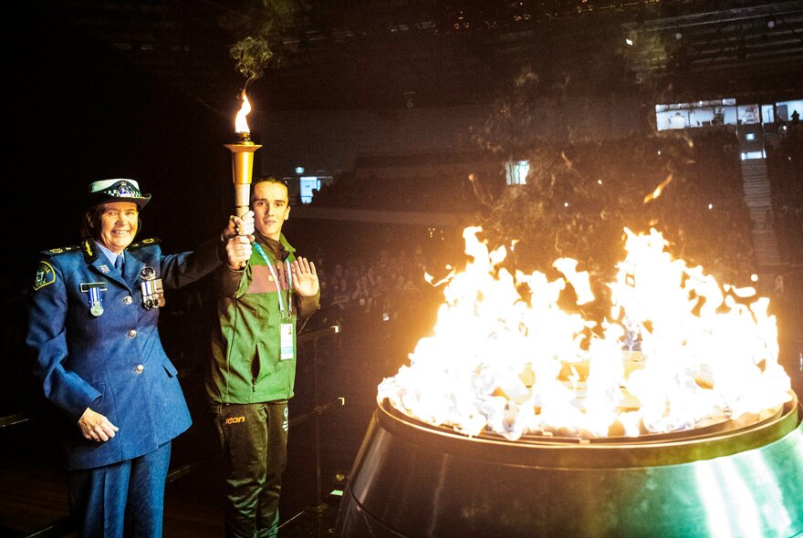 Two people lighting the flame with the torch of hope at the opening ceremony for the Australian Special Olympics national games.