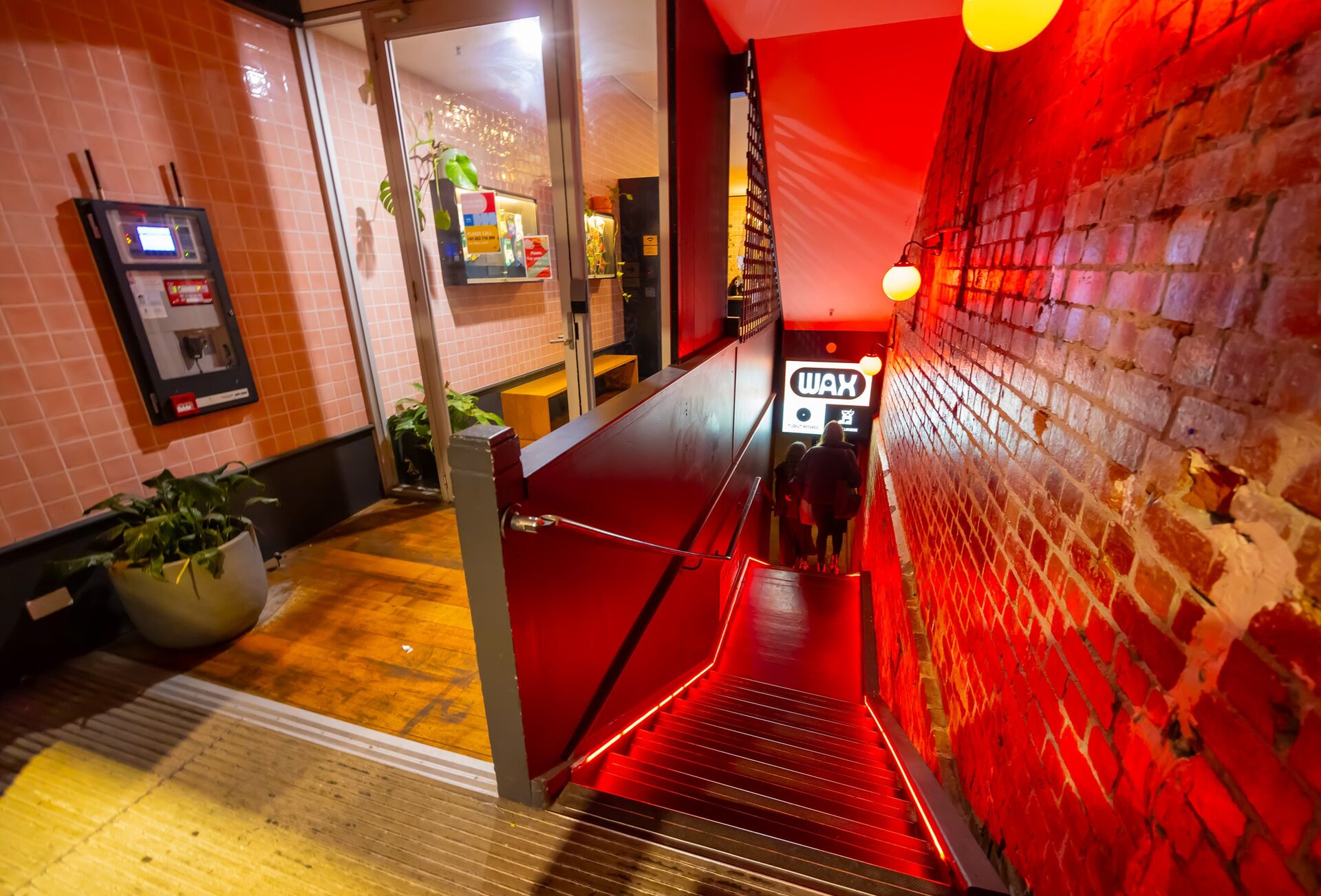 Two friends are walking down some stairs into a hidden basement bar. 