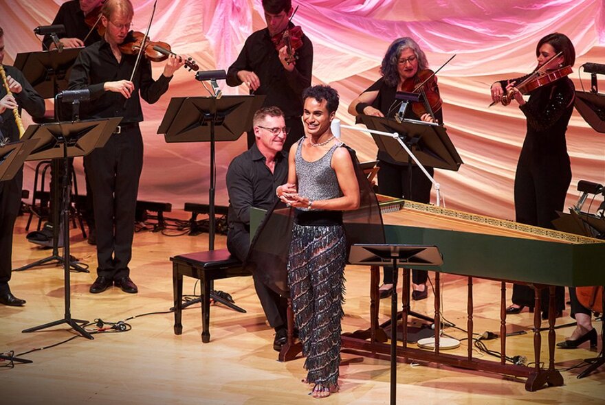 Singer Samuel Mariño standing in front of musicians playing instruments on a stage.