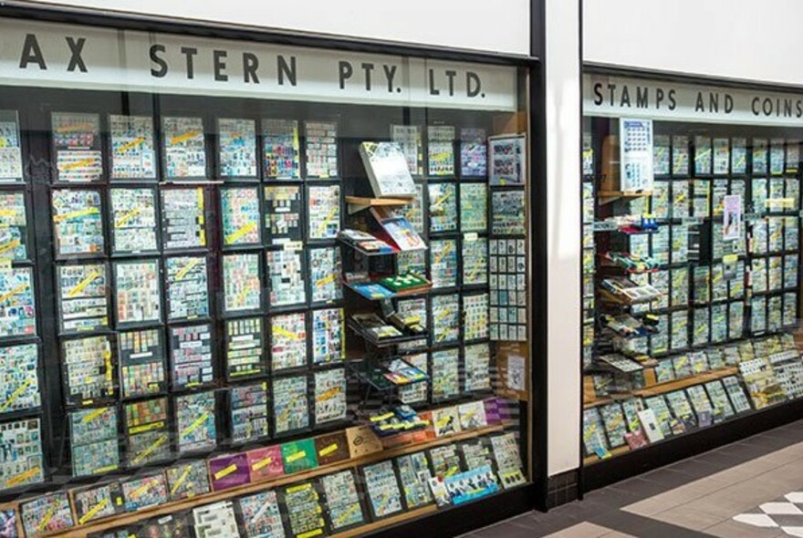 Large wall sized glass cabinet display of stamps and coins.