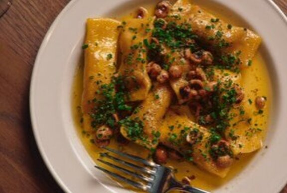 Looking down at a white plate with pasta in a creamy sauce, a fork resting on the side of the plate.