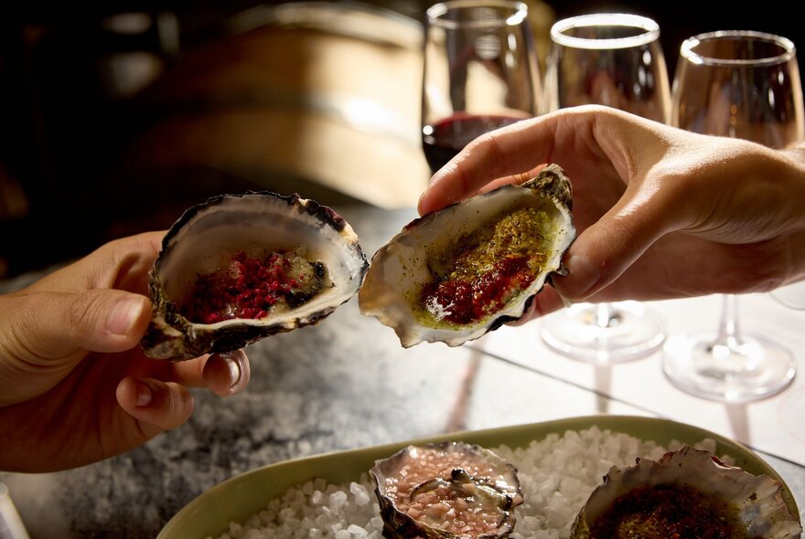 Two hands holding oysters.