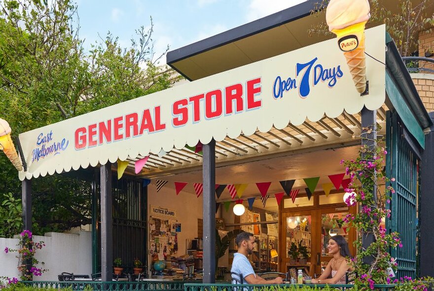 Two friends are sitting in front of a general store