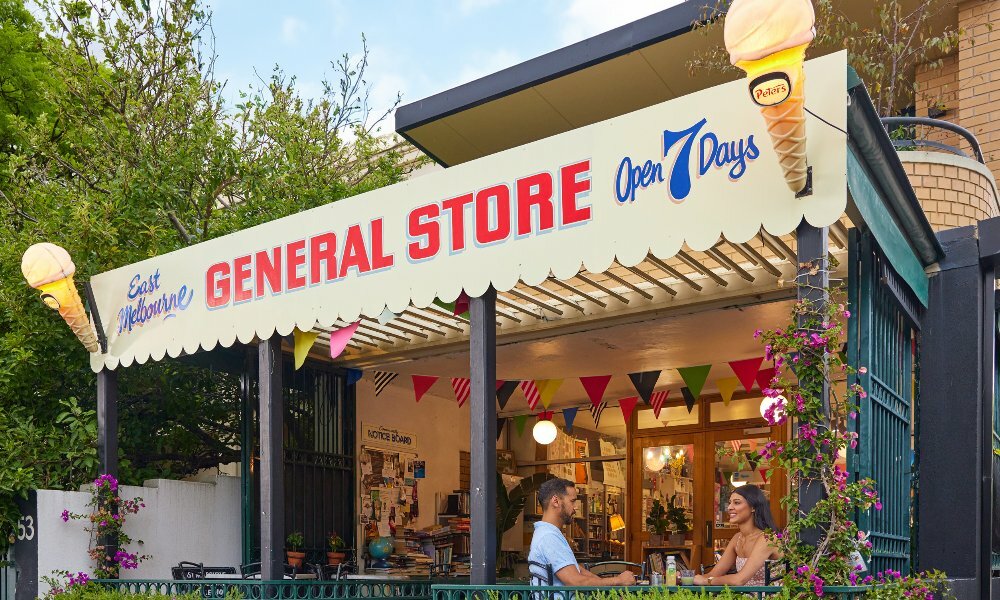 Two friends are sitting in front of a general store