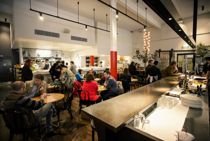 A busy restaurant with an open kitchen and industrial design