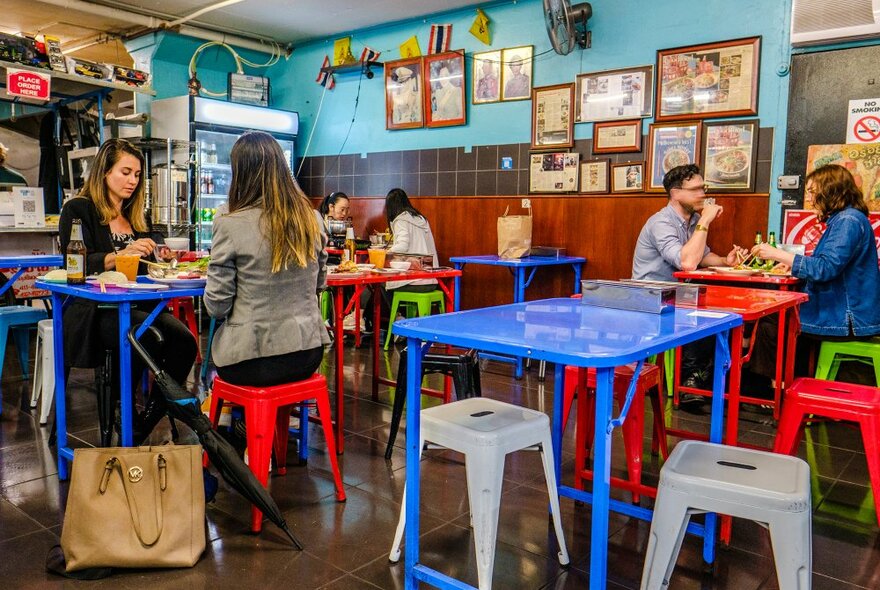 A group of people are eating in a small Thai restaurant.