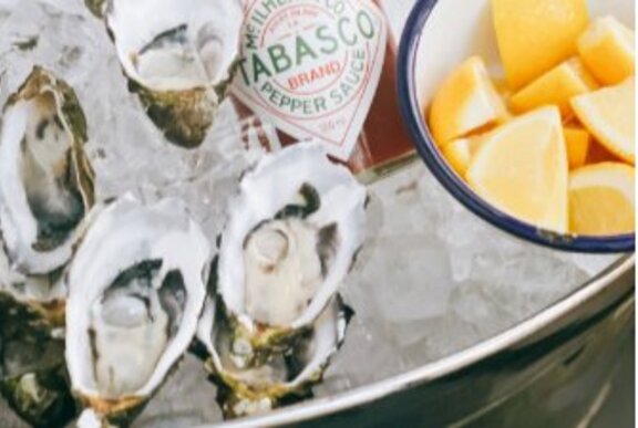 Silver bucket of oysters with Tabasco sauce and lemon.
