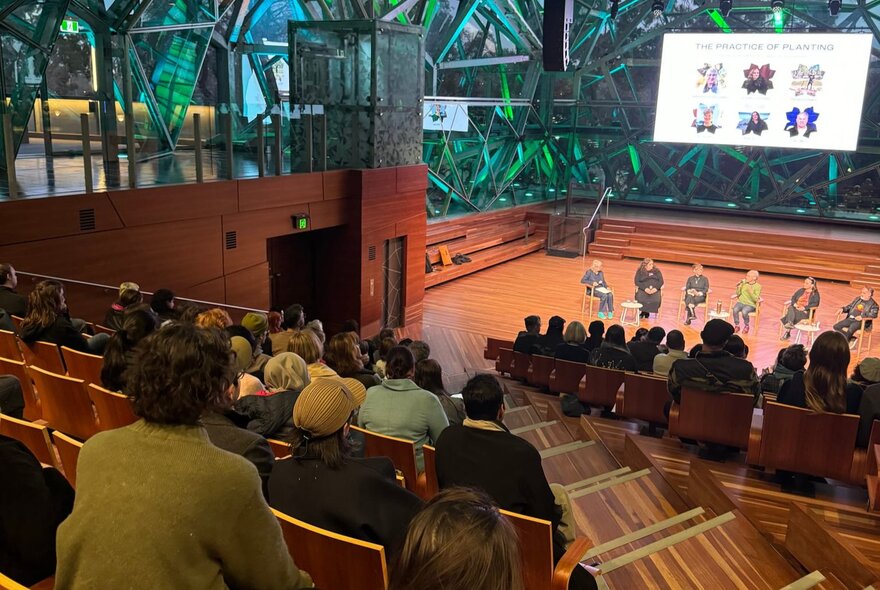 A panel discussion taking place at The Edge in Federation Square, with a seated audience listening to the speakers on stage.