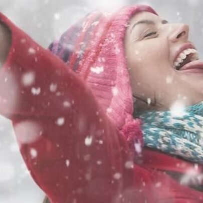 A woman in a red coat and beanie enjoying the snow.