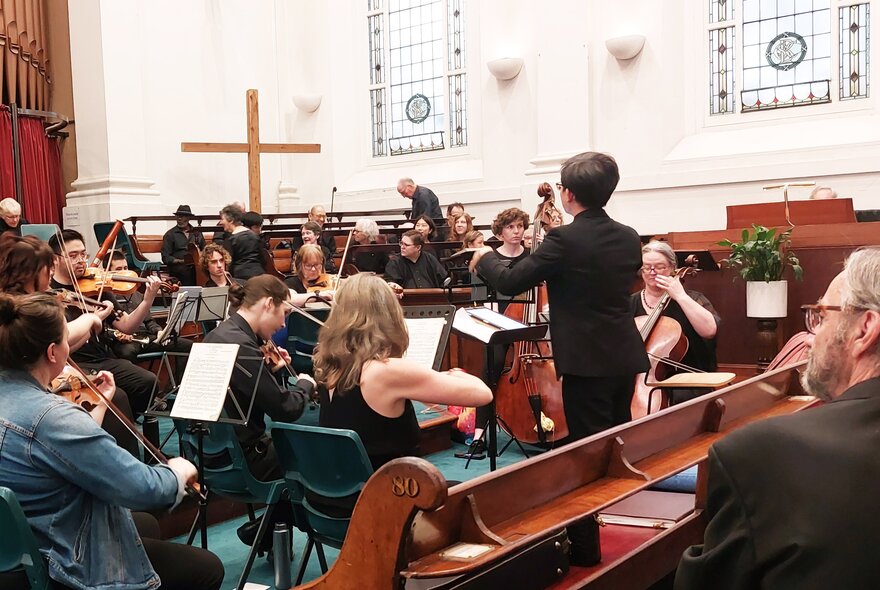 Conductor leading musicians in a Baptist church setting.