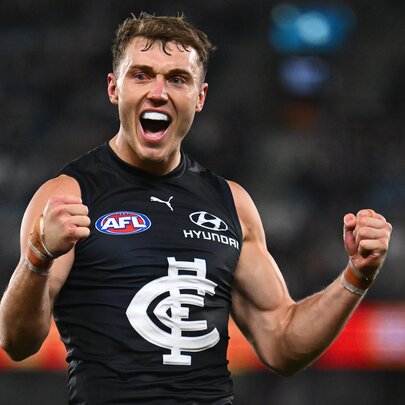 A Carlton AFL football player with his fists clenched and pumped up during a match.
