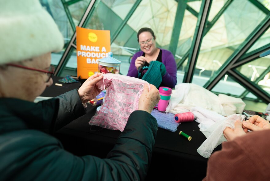 Presenter and attendees holding recycled clothing at a workshop in the Atrium at Fed Square.