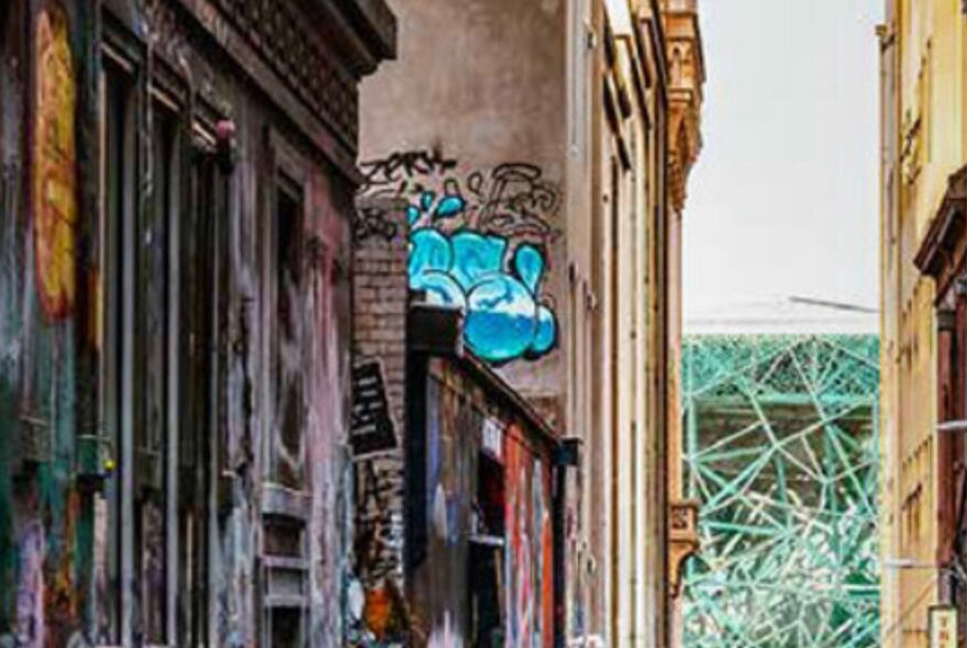 Melbourne laneway with grafitti on distressed old buildings and scaffolding detail of Fed Square in the distances.