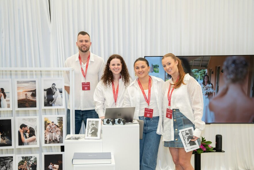 Four people in white at a stall at a bridal expo. 
