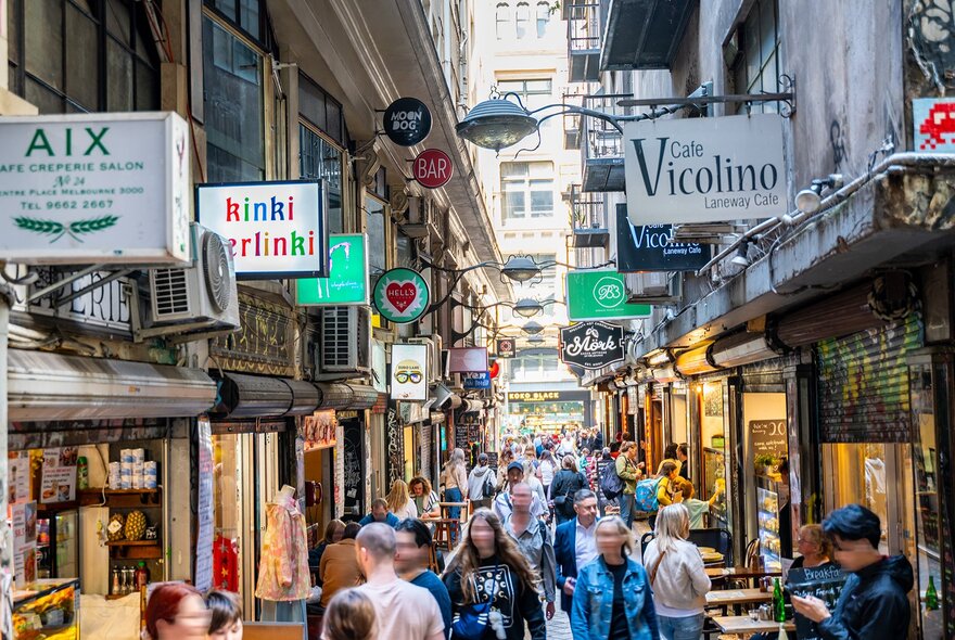 A busy laneway with signs for cafes.