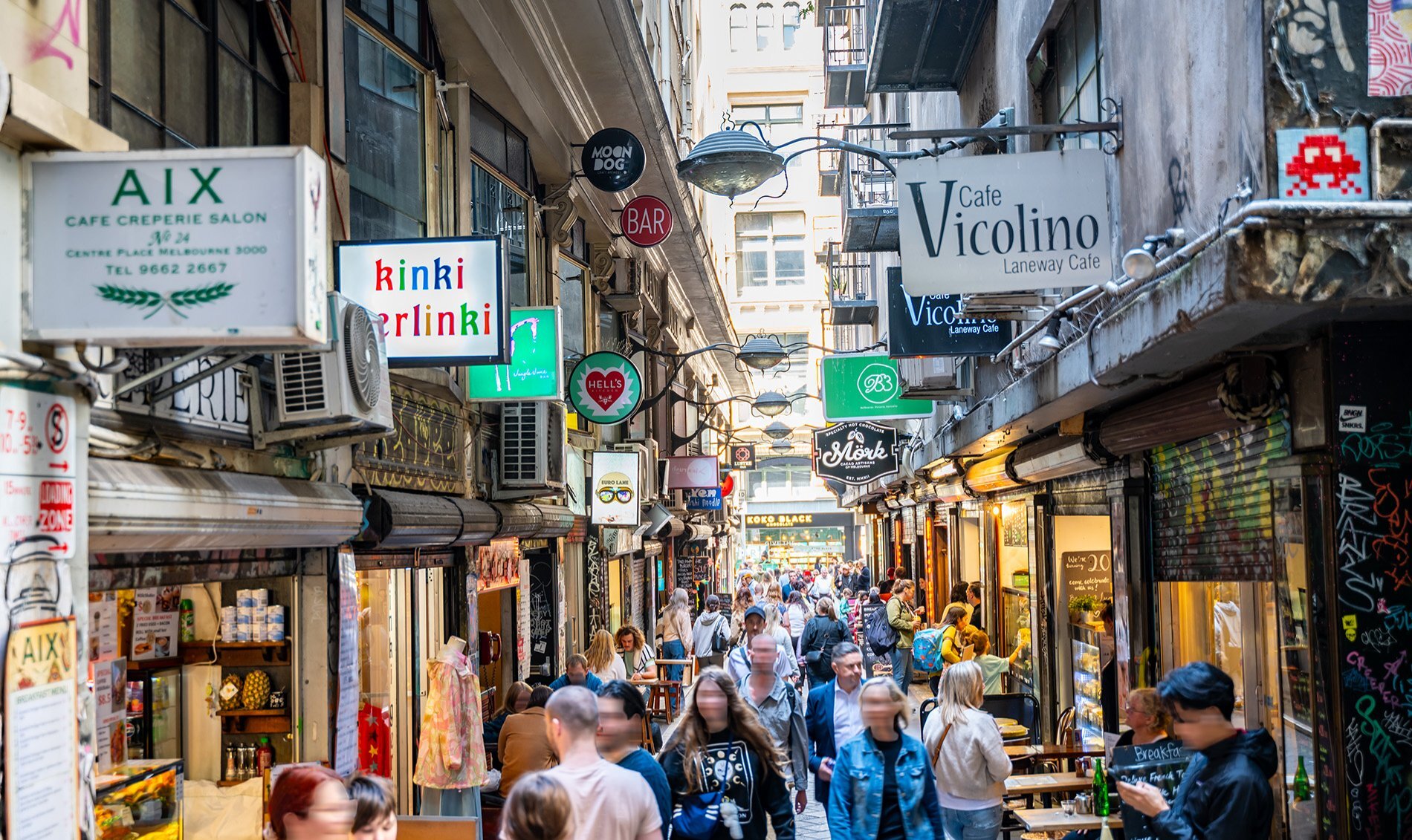 A busy laneway with signs for cafes.