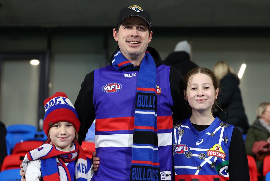 A family of Western Bulldogs footy fans wearing their team colours and scarves.