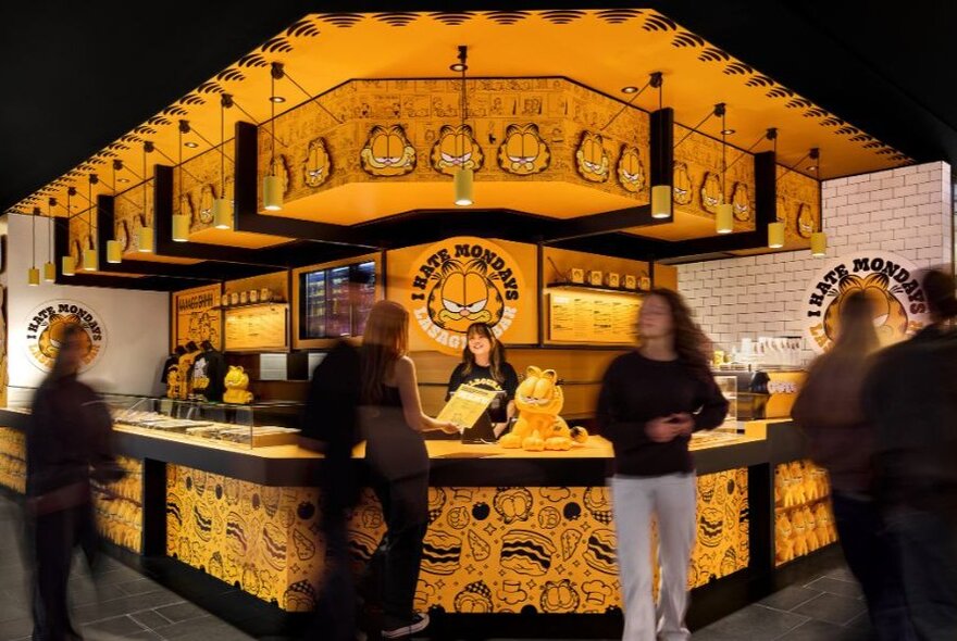 People milling around a yellow pop-up pizza bar with wraparound counter.