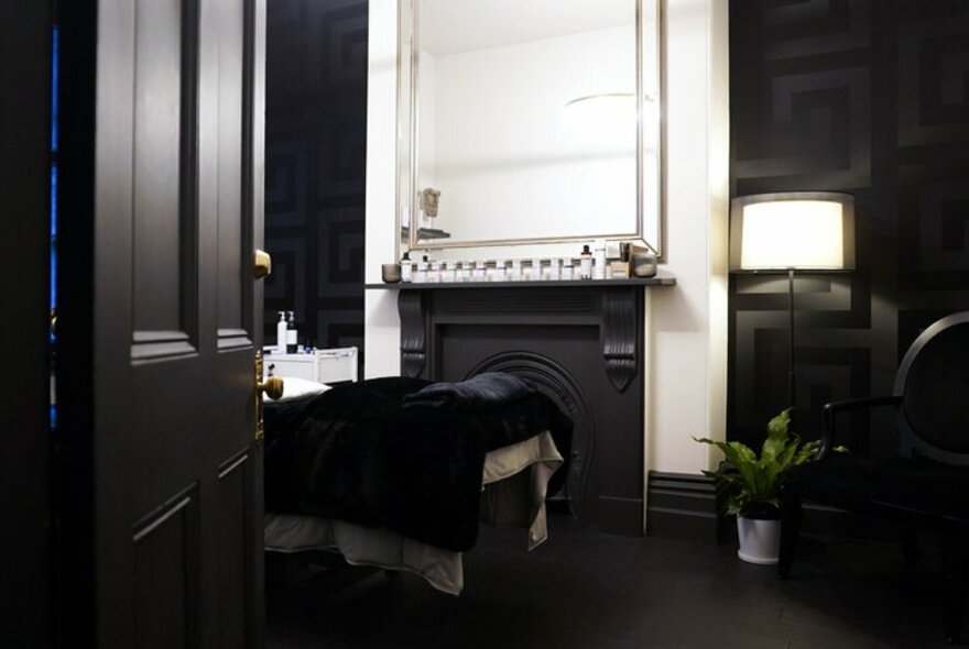 A private beauty therapy room with darkened tones and a black door in the foreground.