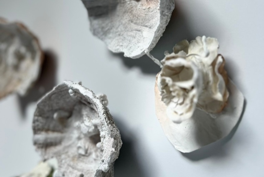 Small ornamental sculptures displayed on a white gallery wall.