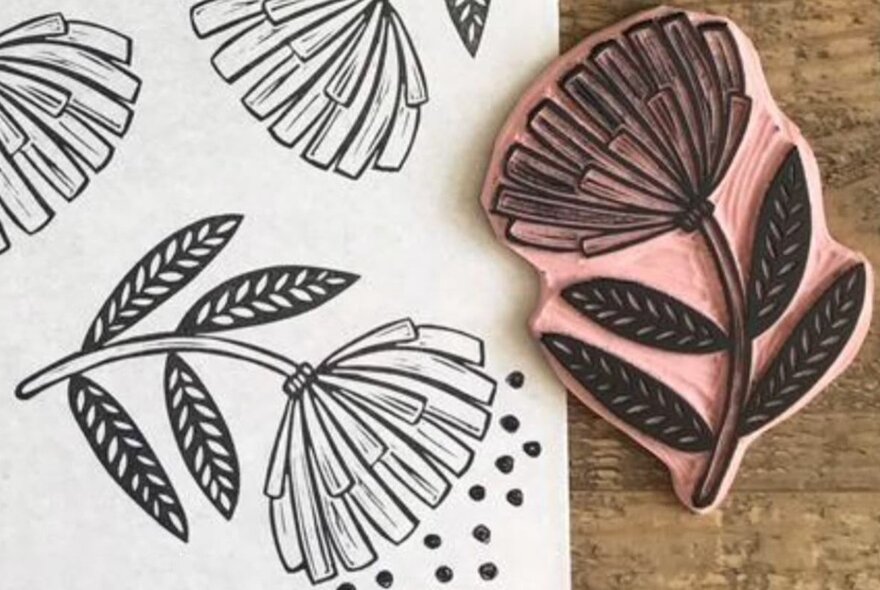 A linocut of a flower and printed results on paper.