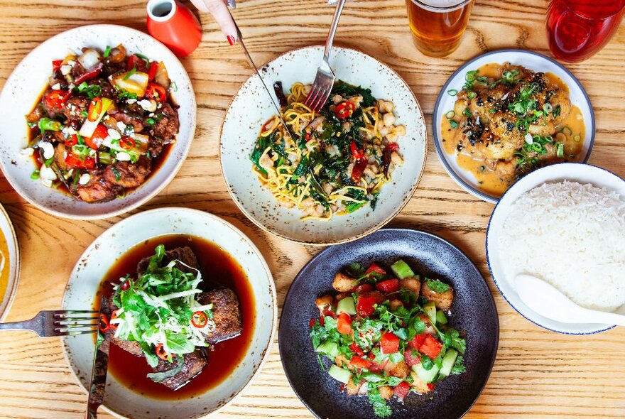 Overhead view of plates of food arranged on a wooden table.