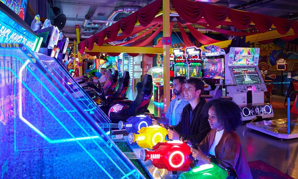 Three friends are playing arcade games