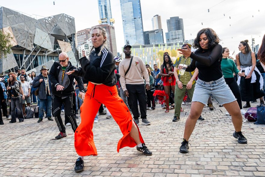 Two Afro-Caribbean dancers at Melbourne's Fed Square, with a crowd watching on behind them.