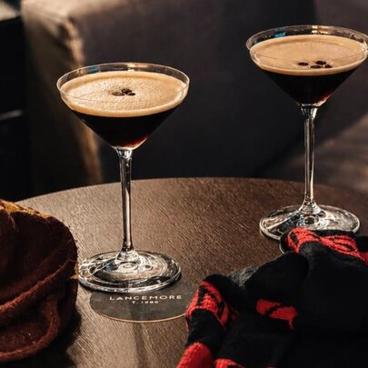 Two espresso martinis on a table with Hawthorn and Essendon scarves
