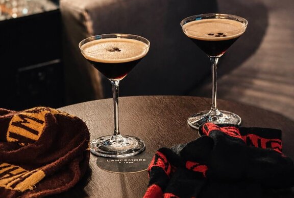 Two espresso martinis on a table with Hawthorn and Essendon scarves